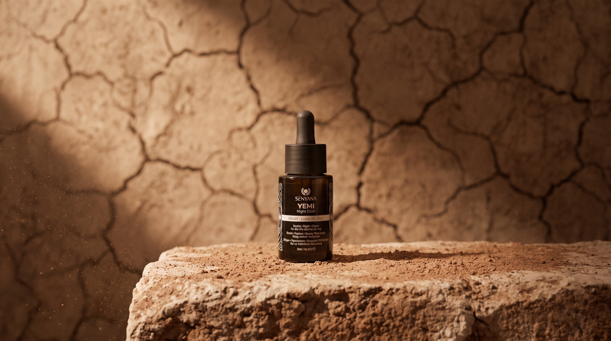 A small amber dropper bottle labeled VITALITY stands on a rough stone surface against a cracked earth wall under warm directional light.